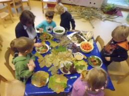 Mehrere Kinder sitzen an einem Tisch mit Herbstblättern
